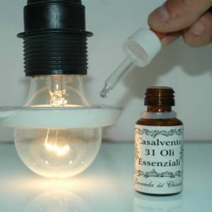 Ceramic ring to diffuse essential oils applied on an incandescent lamp with a dosing pipette and a yellow glass pharmaceutical bottle with the inscription: "Casalvento 31 essential oils"