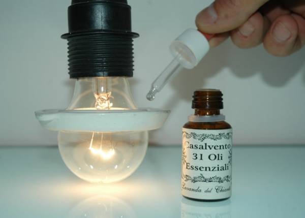 Ceramic ring to diffuse essential oils applied on an incandescent lamp with a dosing pipette and a yellow glass pharmaceutical bottle with the inscription: "Casalvento 31 essential oils"