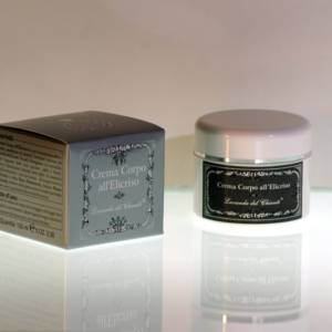 Body cream in a white plastic jar with silver line and silver box with white writing: "Helichrysum body cream". Bright light background with reflections on the table top