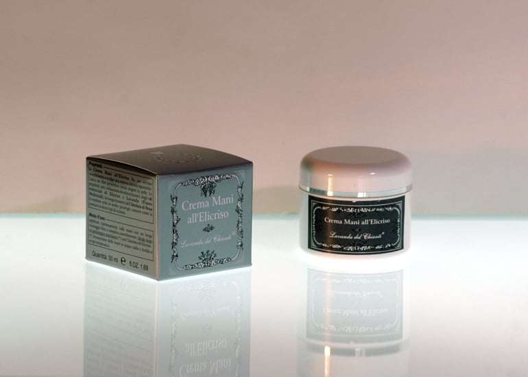 A plastic jar of hand cream with a silver line and a silver box with the inscription: "Helichrysum hand cream". Bright light background