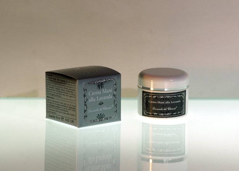 White plastic jar with silver line and dark silver label with the writing: "Lavender hand cream" and silver box with the writing: Lavanda del Chianti" on a light, gray shaded background