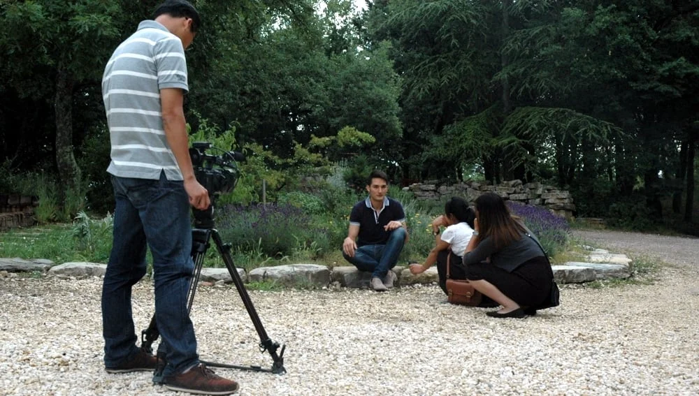 Giornalisti vietnamiti e cineoperatore in una fase delle riprese televisive a Casalvento. Intervista ad Alessandro Domini con sfondo alberato