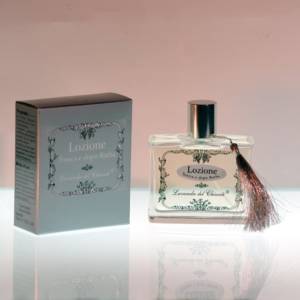 Transparent glass bottle silk-screened with the writing "Chianti lavender tonic and aftershave lotion" with elegant silver soft seal and silver box on a light background and reflections on the support surface