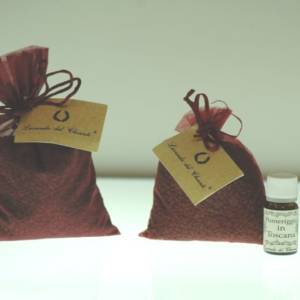 Wine-colored bags with grape seeds and a yellow card with the writing "Lavanda del Chianti" and two bottles of Casalvento essential oils on a bright white background