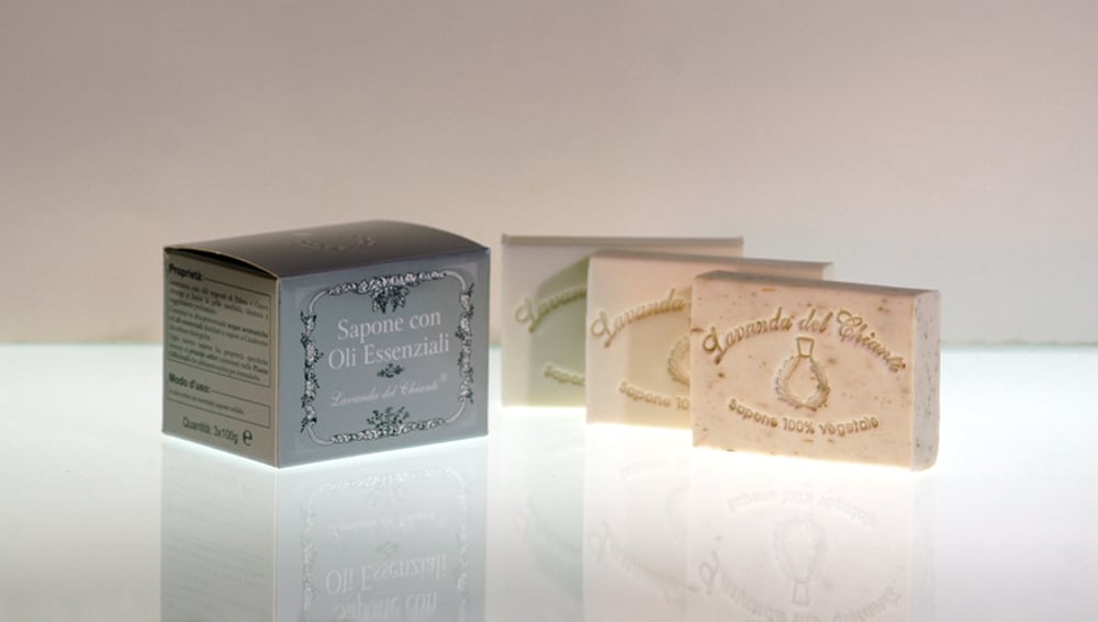 On a bright light background, three rectangular vegetable soaps with the words: "Lavanda del Chianti" and a silver cardboard box