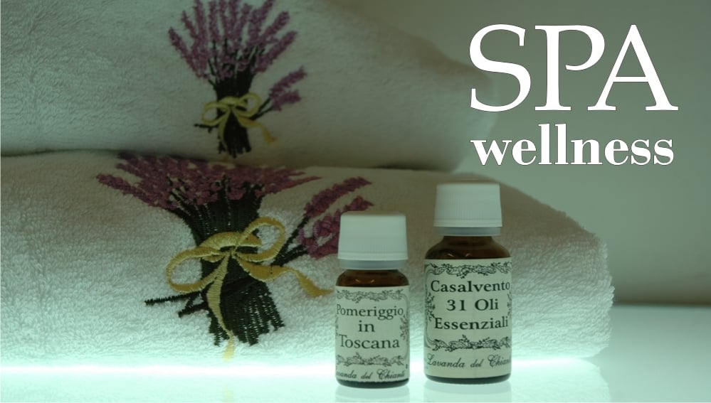 On a bright light background 2 cotton towels with a bunch of lavender flowers embroidered in color and white writing: "Benessere SPA" and 2 yellow pharmaceutical glass bottles with written label: Casalvento 31 Essential Oils